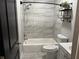 Charming bathroom with tiled walls and floor, shower-tub combo, and decorative shelving at 3646 Sherertz Road, Lakeland, FL 33810