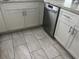 Close-up of the kitchen featuring tiled floors, white cabinetry, gray counters, and stainless steel dishwasher at 3646 Sherertz Road, Lakeland, FL 33810