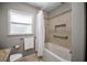Bright bathroom featuring a shower over tub with decorative tile border and a frosted window at 4006 Glen Garry W Rd, Lakeland, FL 33813