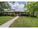 Charming brick home featuring a metal roof and lush landscaping in the front yard at 4006 Glen Garry W Rd, Lakeland, FL 33813