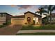Charming single-story home featuring a well-manicured lawn, brick driveway, and a terracotta tiled roof at 4088 Prima Lago Cir, Lakeland, FL 33810
