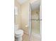 Bright bathroom featuring a walk-in shower with safety bar and standard toilet with beige tiling at 4219 Sunny Land Dr, Lakeland, FL 33813