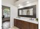 Bathroom showcasing dual sinks with a large dark-framed mirror, dark wood cabinets, and wood-look tile at 4642 Highlands Place Dr, Lakeland, FL 33813