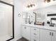 Modern bathroom features dual sinks, white cabinets, black hardware, and a tiled shower at 485 Silverbell Trl, St Cloud, FL 34771