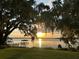 Scenic sunset view of a lake with a private dock and lush greenery, creating a serene and inviting atmosphere at 5026 N Socrum Loop Rd, Lakeland, FL 33809