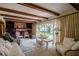Cozy living room features wood beams, brick fireplace, built-in shelves and sliding doors with a lake view at 5026 N Socrum Loop Rd, Lakeland, FL 33809