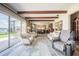 Open concept living room and dining area with wood beam ceiling and large windows overlooking the lake at 5026 N Socrum Loop Rd, Lakeland, FL 33809