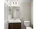 Bright bathroom featuring a vanity with brown cabinets, marble countertop, and white toilet at 5771 Freshwater Canyon Dr, St Cloud, FL 34771