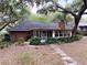 The back of the house features a brick chimney and a enclosed back porch with a stone walkway at 6116 Sweet Gum Run, Bartow, FL 33830