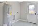 Bright laundry room with a gray water heater, a white floor, and a door with glass panels at 727 S Missouri Ave, Lakeland, FL 33815