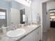 Bathroom with double sinks and a mirror, and a glimpse into an adjacent room at 867 Cypress Creek Run, St Cloud, FL 34771