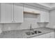 This kitchen features a stainless steel sink, granite countertops and bright white cabinets at 1017 Fleming Ave, Lakeland, FL 33815