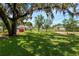 Expansive backyard featuring mature trees, lush lawn, and a charming red storage shed at 111 E Orange St, Davenport, FL 33837