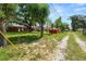 View of gravel driveway and the large backyard featuring mature trees and a charming red storage shed at 111 E Orange St, Davenport, FL 33837