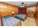 Shared bedroom with wood paneling, two beds, and simple decor at 111 E Orange St, Davenport, FL 33837