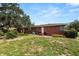 Brick exterior of a house with a grassy yard and mature trees at 111 E Orange St, Davenport, FL 33837