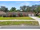 Charming single-story brick home with manicured lawn, mature shrubs, and an attached two-car garage at 111 E Orange St, Davenport, FL 33837