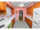 Galley kitchen featuring retro wood cabinets, ample counter space, a white refrigerator, and traditional appliances at 111 E Orange St, Davenport, FL 33837
