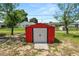 Small, red storage shed situated in a grassy yard with a few trees at 111 E Orange St, Davenport, FL 33837