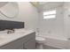 Bathroom with a gray vanity, a round mirror, and a tiled shower-tub combination at 113 Patrick Henry Rd, Bartow, FL 33830