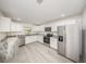 Modern kitchen features stainless steel appliances, ample white cabinetry, and elegant marble countertops, with durable light gray flooring at 113 Patrick Henry Rd, Bartow, FL 33830