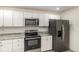 Kitchen boasting white cabinets, stainless steel appliances, gray marble countertops, and durable light gray flooring at 113 Patrick Henry Rd, Bartow, FL 33830
