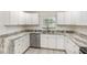Kitchen featuring white cabinets, stainless steel dishwasher and sink, granite countertops, and durable light gray flooring at 113 Patrick Henry Rd, Bartow, FL 33830