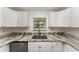 Close-up of the kitchen sink and dishwasher area with white cabinets and countertops at 113 Patrick Henry Rd, Bartow, FL 33830
