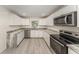 Bright kitchen features white cabinets, stainless steel appliances, gray marble countertops, and durable light gray flooring at 113 Patrick Henry Rd, Bartow, FL 33830