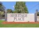 Community sign for Heritage Place featuring a well-maintained landscaped area with manicured plants and fresh mulch at 113 Patrick Henry Rd, Bartow, FL 33830