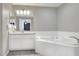 Bright bathroom boasts a tiled corner tub, tile floors, and a large vanity with granite countertop at 1140 Stratton Ave, Groveland, FL 34736