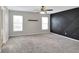Spacious bedroom with neutral walls, carpet floors, black accent wall, and natural lighting from two windows at 1140 Stratton Ave, Groveland, FL 34736