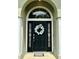 Close up of front door with welcome mat and a white floral wreath with sidelights and large arched window at 1140 Stratton Ave, Groveland, FL 34736