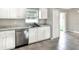 White kitchen with stainless steel dishwasher, sink, solid surface countertops, and view of the backyard at 1140 Stratton Ave, Groveland, FL 34736