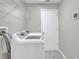 Bright laundry room with modern washer and dryer units, shelving, and tile floors at 1140 Stratton Ave, Groveland, FL 34736