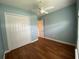Bedroom with a ceiling fan, blue walls, wood floors, and a closet at 1167 Motorcoach Dr, Polk City, FL 33868
