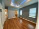 Well-lit main bedroom features wood floors, tray ceiling, two windows, and ensuite bathroom at 1167 Motorcoach Dr, Polk City, FL 33868