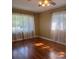 Bright bedroom featuring polished hardwood floors, large windows with sheer curtains, and a ceiling fan for comfort at 1215 E Edgewood Dr, Lakeland, FL 33803