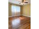 Inviting bedroom with hardwood floors, a ceiling fan, and a window dressed with sheer curtains, offering natural light at 1215 E Edgewood Dr, Lakeland, FL 33803