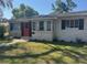 Charming brick home with a well-maintained front lawn, complemented by a red door and black shutters at 1215 E Edgewood Dr, Lakeland, FL 33803