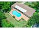 Aerial view of a kidney-shaped pool with brick coping next to a single story home in a lush setting at 1235 Lake Point Dr, Lakeland, FL 33813