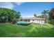 View of the backyard with a beautiful pool, green lawn, and mature trees from the opposite side at 1235 Lake Point Dr, Lakeland, FL 33813