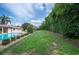 The backyard shows off a swimming pool, lush greenery, tall hedges, and beautiful blue skies at 1235 Lake Point Dr, Lakeland, FL 33813