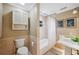 Well-lit bathroom featuring a toilet, cabinet, and a tub with neutral toned stone tile and elegant fixtures at 1235 Lake Point Dr, Lakeland, FL 33813