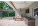 Outdoor kitchen under a covered patio area with a grill, storage, and a sink for easy outdoor cooking at 1235 Lake Point Dr, Lakeland, FL 33813