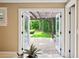 Patio view, accessible through double glass doors, features a pergola and lush landscaping, perfect for outdoor relaxation at 1235 Lake Point Dr, Lakeland, FL 33813