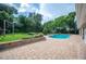 A kidney-shaped pool is bordered by a brick patio, lush greenery, and a swing set in this backyard oasis at 1235 Lake Point Dr, Lakeland, FL 33813