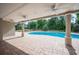Covered patio overlooking pool and landscaped backyard featuring brick pavers and manicured hedges and trees at 1235 Lake Point Dr, Lakeland, FL 33813