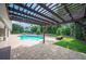 Backyard pool featuring a brick paver patio, pergola, and lush landscaping offers a great outdoor living space at 1235 Lake Point Dr, Lakeland, FL 33813
