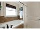 Bathroom featuring a soaking tub with tile surround, natural light, and a shower curtain at 1825 Pawnee Trl, Lakeland, FL 33803